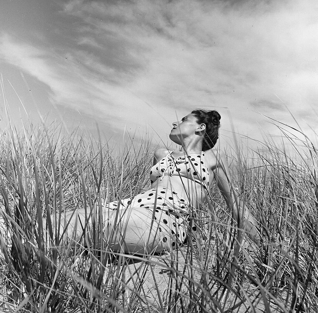 #119 Portrait of a woman wearing a polka dot bathing suit and seated among the plants on the beach, Provincetown, Massachusetts, 1948.
