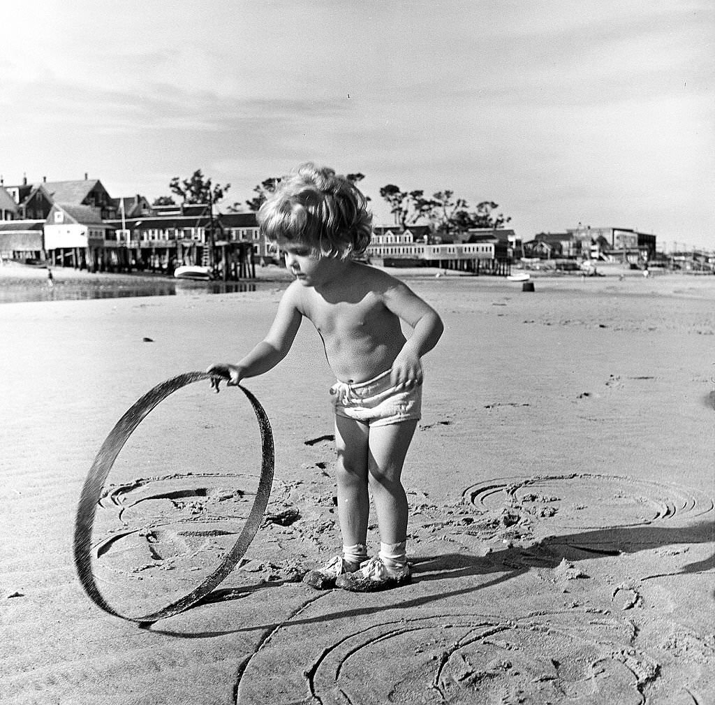 #122 A young child plays with a hoop on the beach, Provincetown, Massachusetts, 1948.