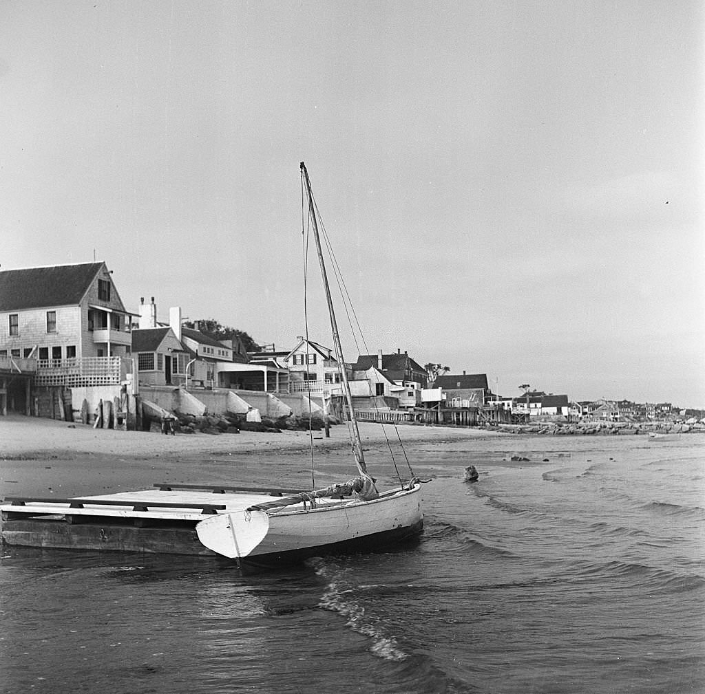 #127 View of a small sailboat docked to a beached raft with beachside houses in the distance, Provincetown, Massachusetts, 1948.