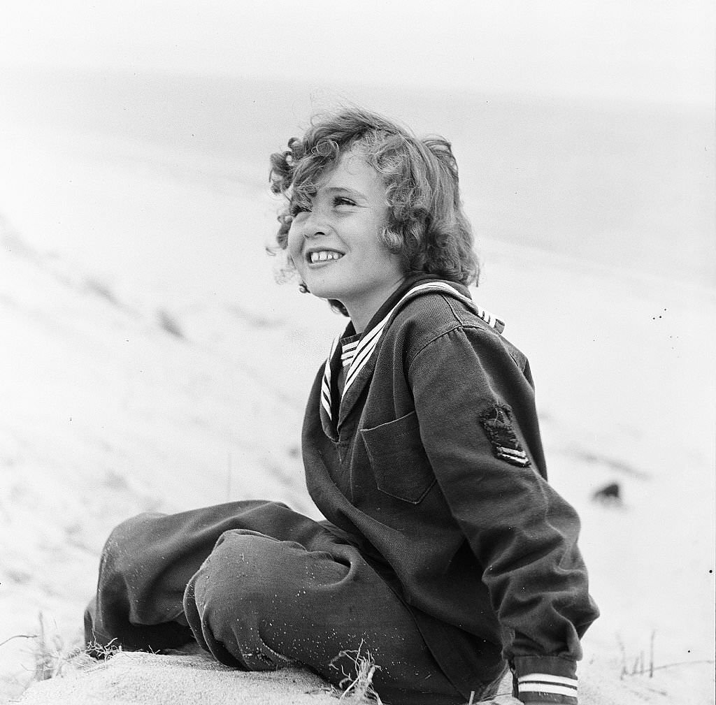 #17 Young girl smiles while sitting on the beach on Cape Cod, Provincetown, Massachussetts, 1947.