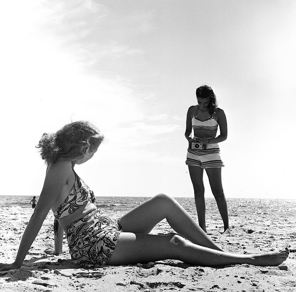 #132 A woman takes a photograph of her friend as they visit the beach, Provincetown, Massachusetts, 1948.