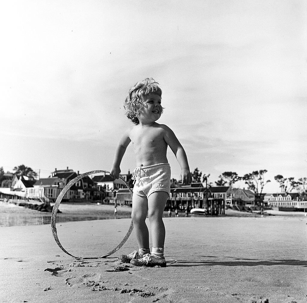 #135 A young child plays with a hoop on the beach, Provincetown, Massachusetts, 1948.