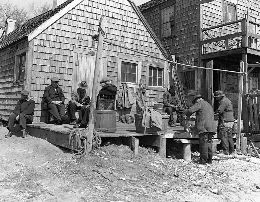 #38 Portuguese dory fishermen sit and talk on the deck of the fishing shack where they store their gear, 1940s