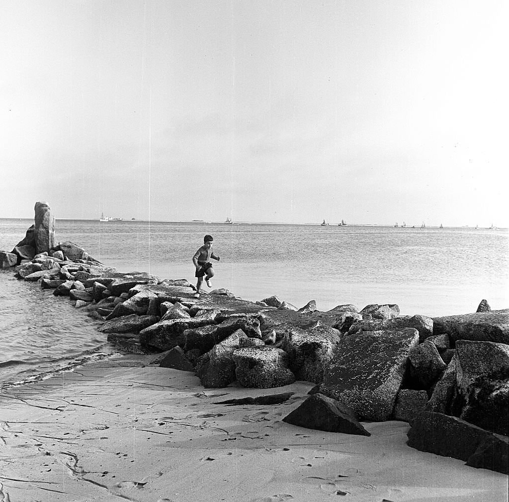 #49 A young boy runs on a rocky breakwater on the beach, Provincetown, Massachusetts, 1948.