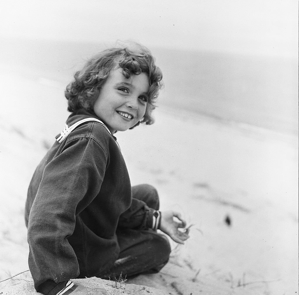 #9 A young girl smiles while sitting on the beach on Cape Cod, Provincetown, Massachussetts, 1947.