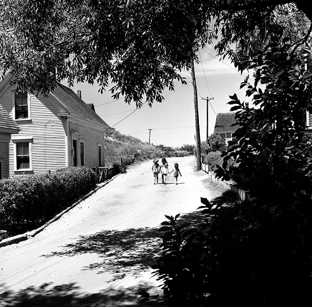 #85 Three children hold hands as they walk up a street, Provincetown, Massachusetts, 1948.