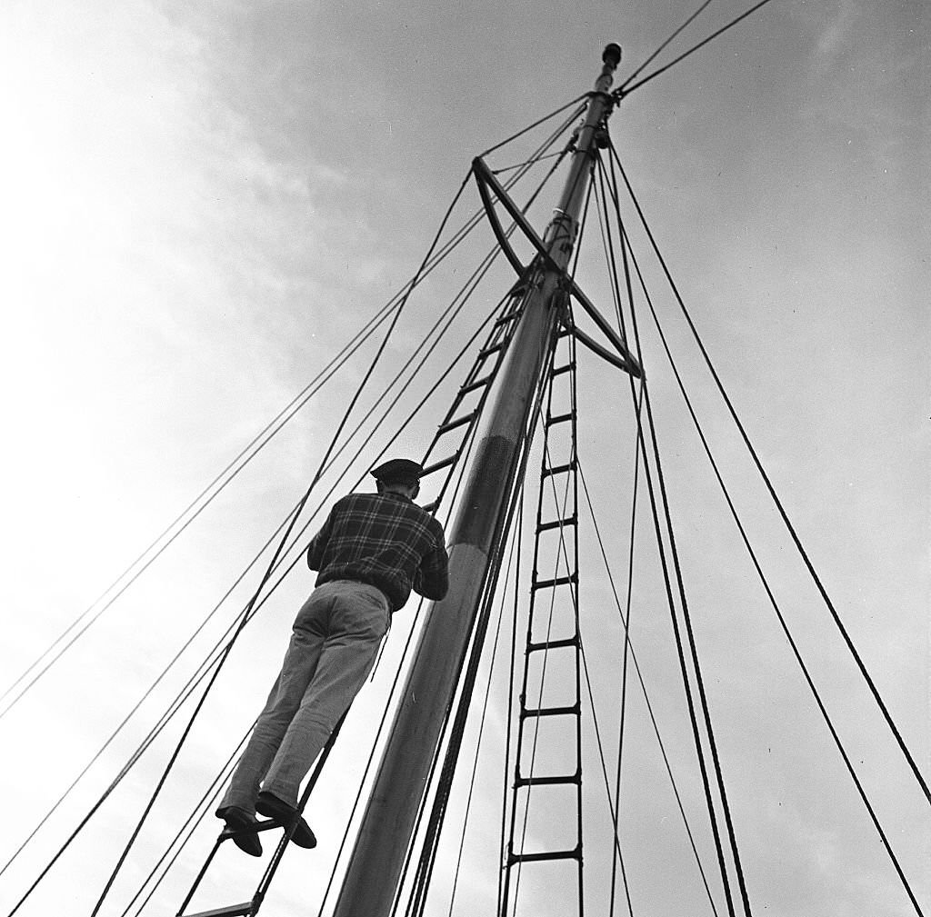 #99 A man climbs up the mast of a sailboat, Provincetown, Massachusetts, 1948.