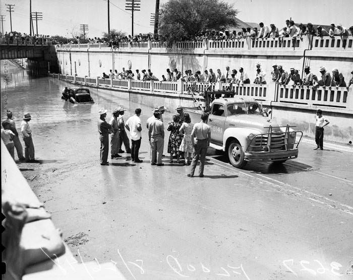 #17 Crowds watch a wrecker pull a car from flooded San Pedro underpass, 1948