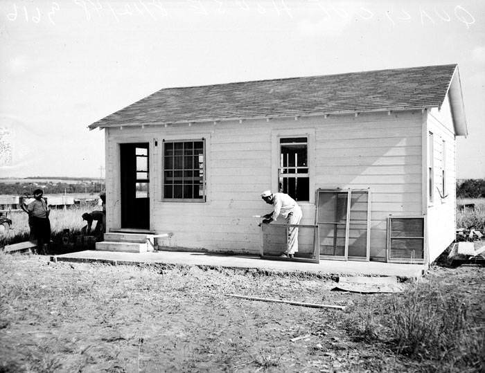 #81 Man prepares to hang window screen on Quali-Cut residence, 1948