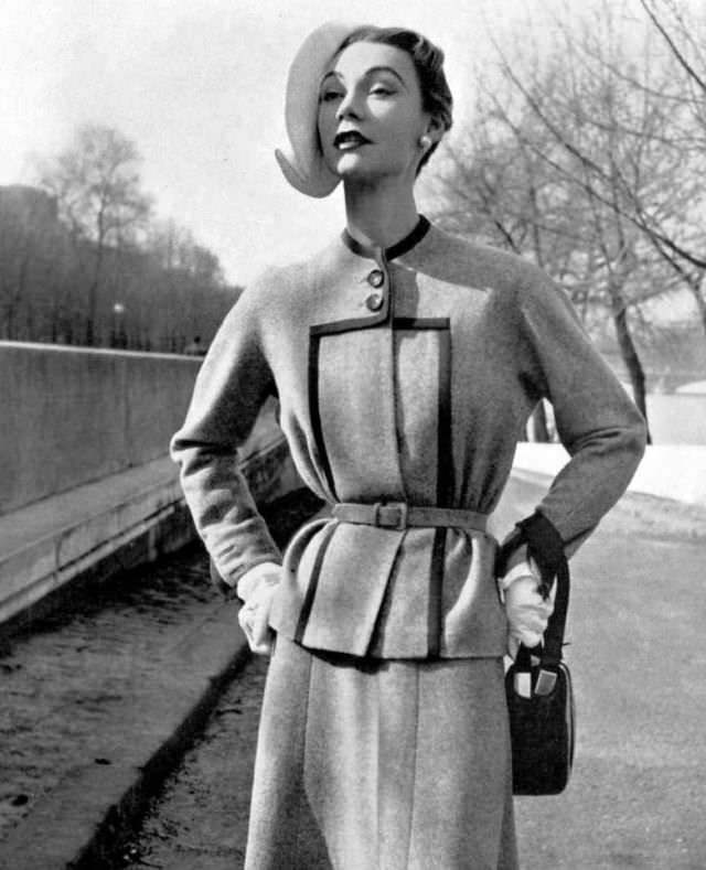 #7 Sophie Malgat in elegant mottled tweed jacket, black braid highlights the neck and front panel, narrow fabric belt marks the waist, skirt is cut on the bias, by Jeanne Paquin, 1952