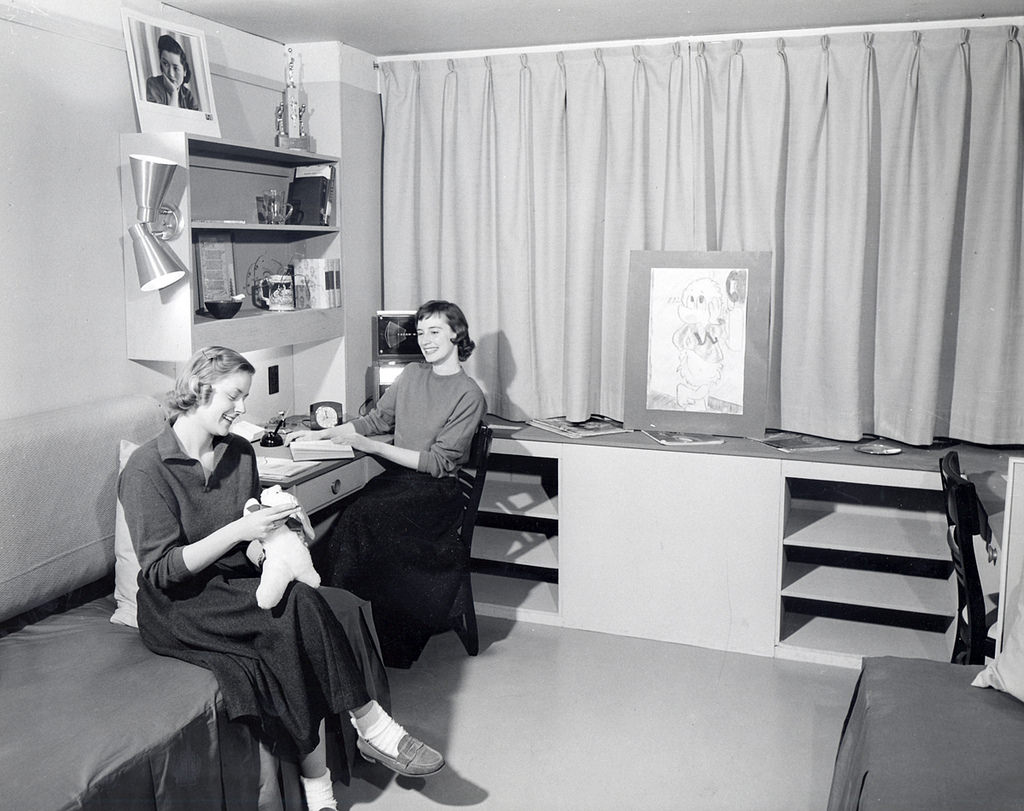 #50 Two women sitting in mock-up dorm room in Chadbourne Hall, 1950s