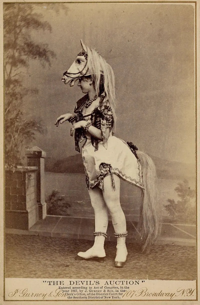 #1 Eliza Blasina wearing horse-head headdress, short costume with attached horsetail, rows of round beads or bells around ankles, wrists, neck and upper arm.