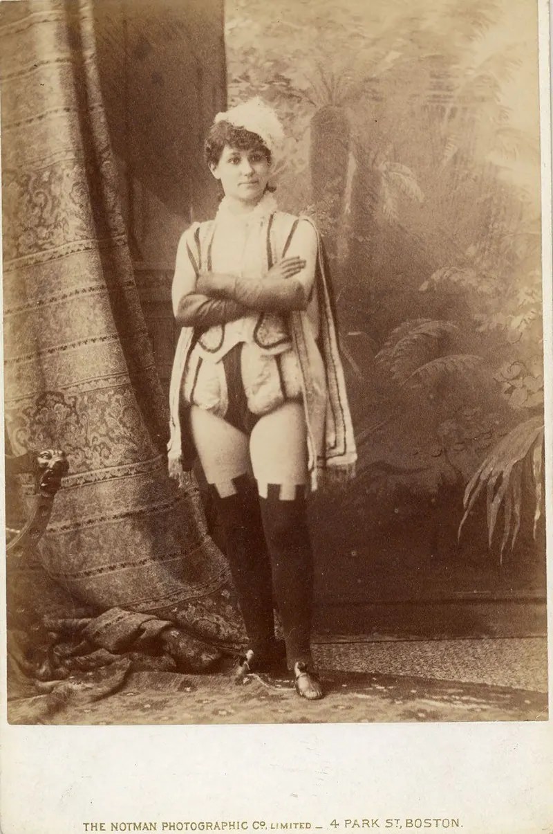 #5 Miss Darcey in short male Renaissance costume with over-the-knee leggings.