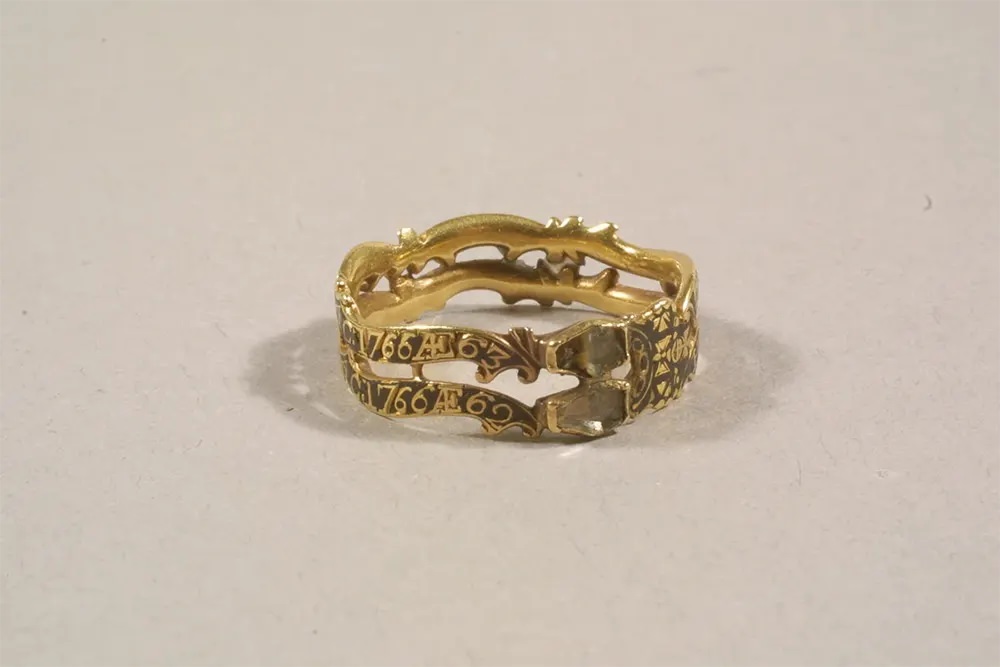 #3 A gold mourning ring with black enamel, featuring two coffin-shaped bezels with faintly visible skeletons.