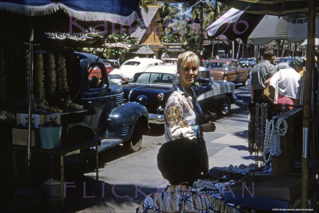 #43 Our pretty blonde snapped amid the lei sellers and tourists on the makai sidewalk of Waikiki’s Kalakaua Avenue, 1960