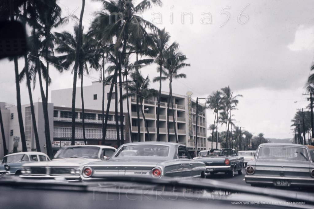#125 Heading Ewa (west) Waikiki’s along busy Kalakaua Avenue at the intersection with Beach Walk, 1964