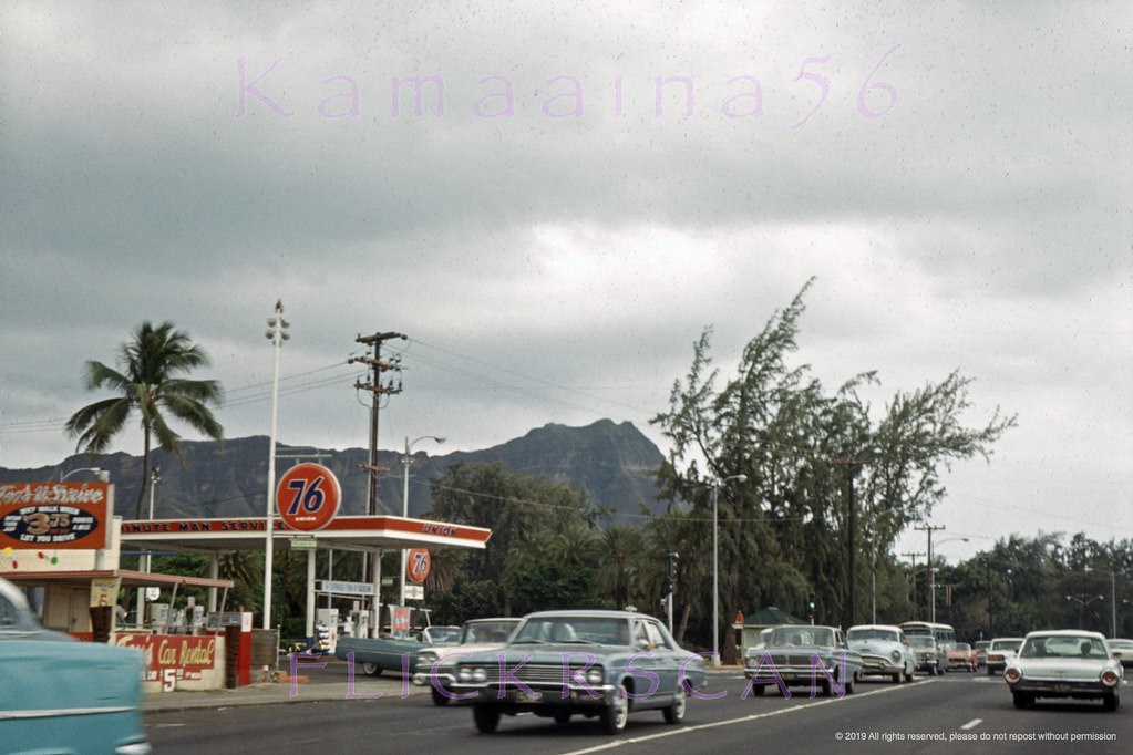 #182 Waikiki’s busy Kalakaua Avenue at the corner of Kapahulu Avenue with Diamond Head Crater in the background, 1965