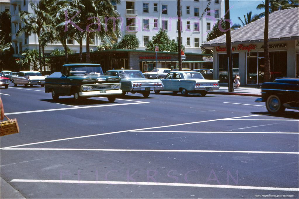 #34 Street level shot taken from the crosswalk of the International Market Place looking makai across Waikiki’s Kalakaua Avenue, 1962