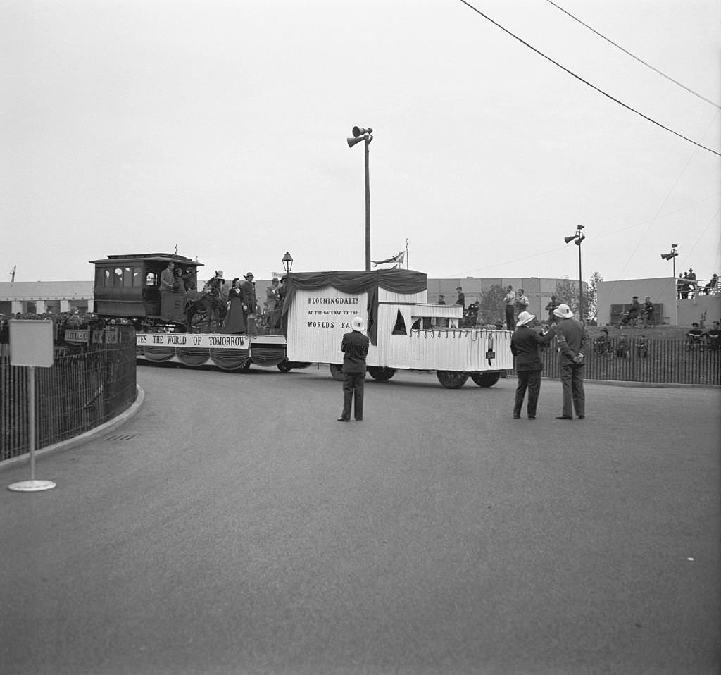 #105 Crowds of people and security staff, watching a carnival float carrying a western type horsedrawn tram and people dressed in 1890’s period costumes, drawn by a motor vehicle.