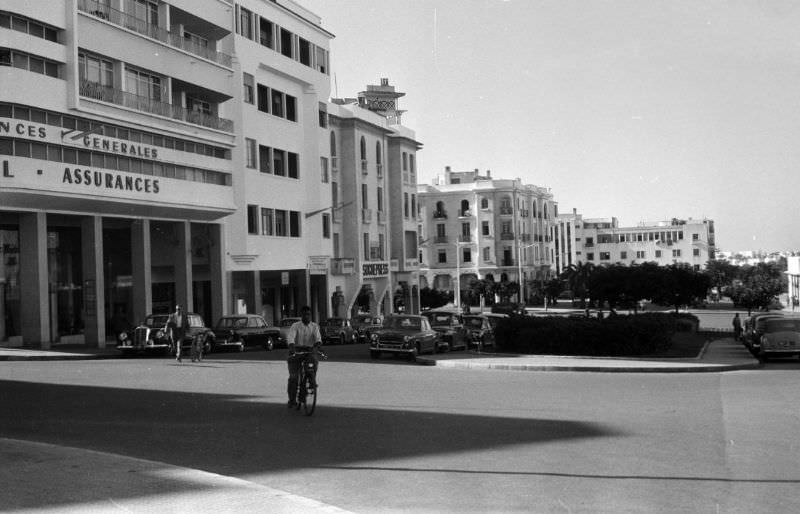 #99 Man bicycling on street in Rabat business district, 1960s
