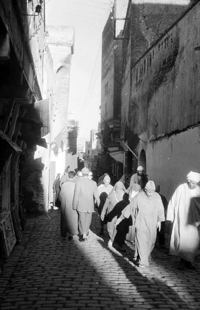 #111 People walking through souk on cobblestone street in Rabat, 1960s