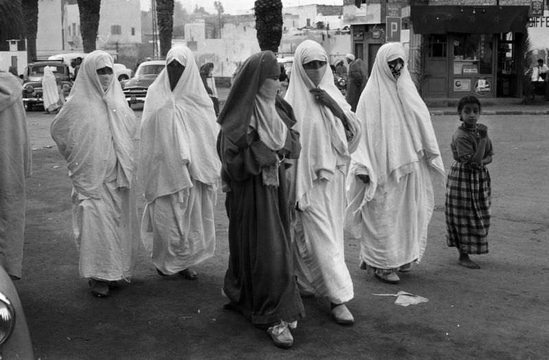 #68 Women in niqabs and abayas walking in street, 1960s