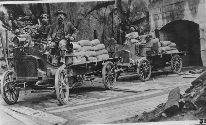 #26 Three men riding in an automobile and trailers for hauling cement, 1906