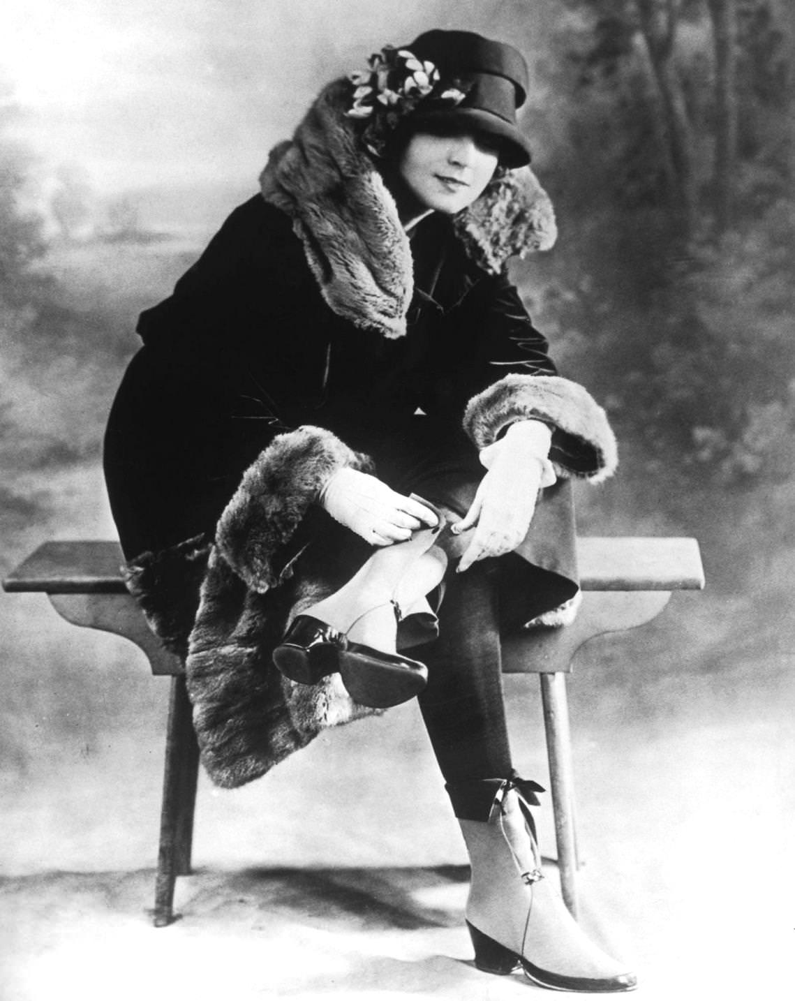 #101 A woman in a winter outfit of fur-trimmed coat and boots with spats, 1925.