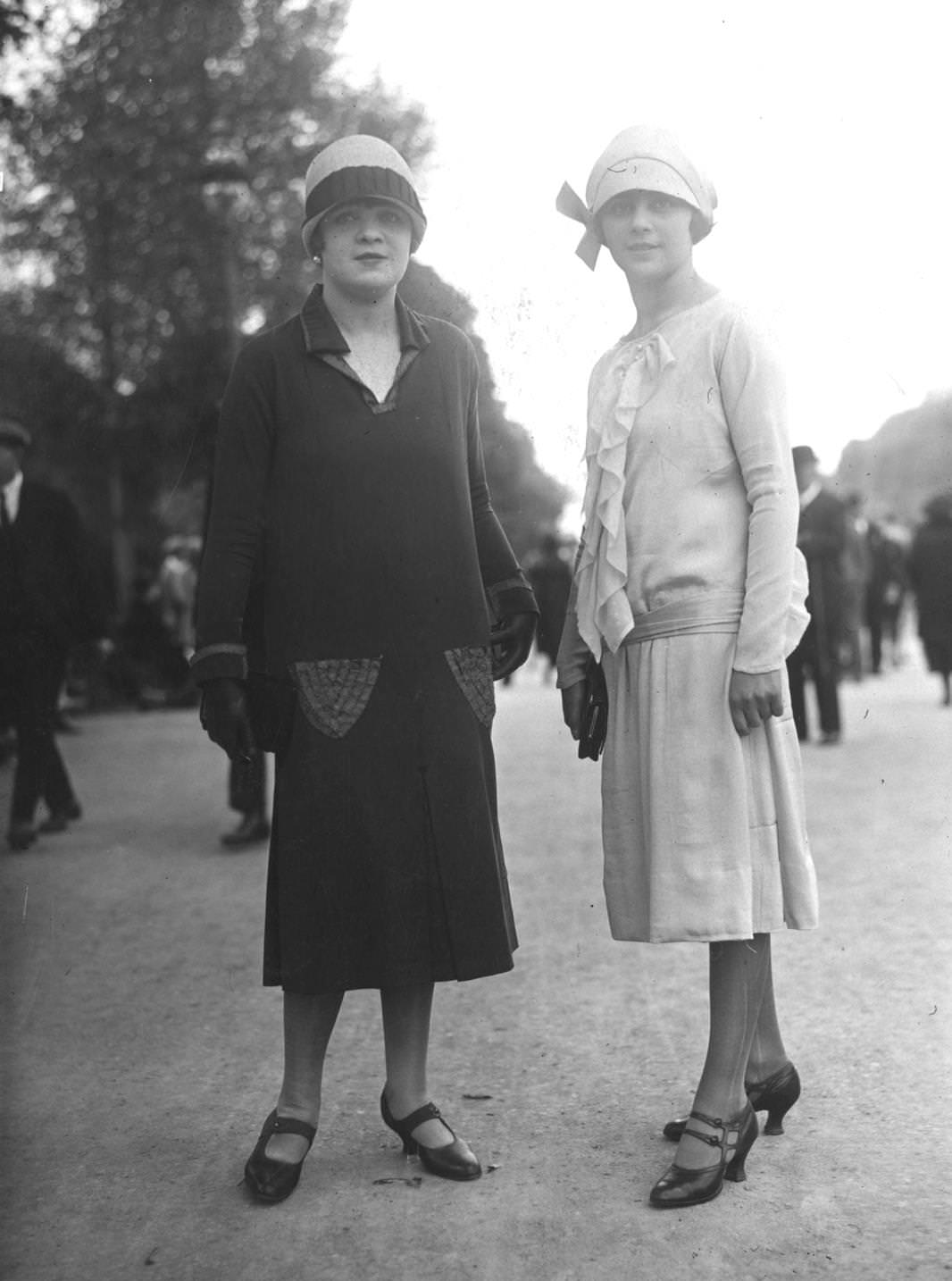 #109 Black drop waist dress with embroidered pocket detail (left), white silk dress with ruffled front and sash belt tied on the hips, 1925