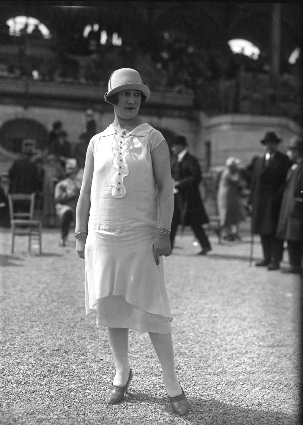 #111 Tunic dress and a cloche hat with a small upturned brim. Dress has very short sleeves and is worn with short gloves, 1925