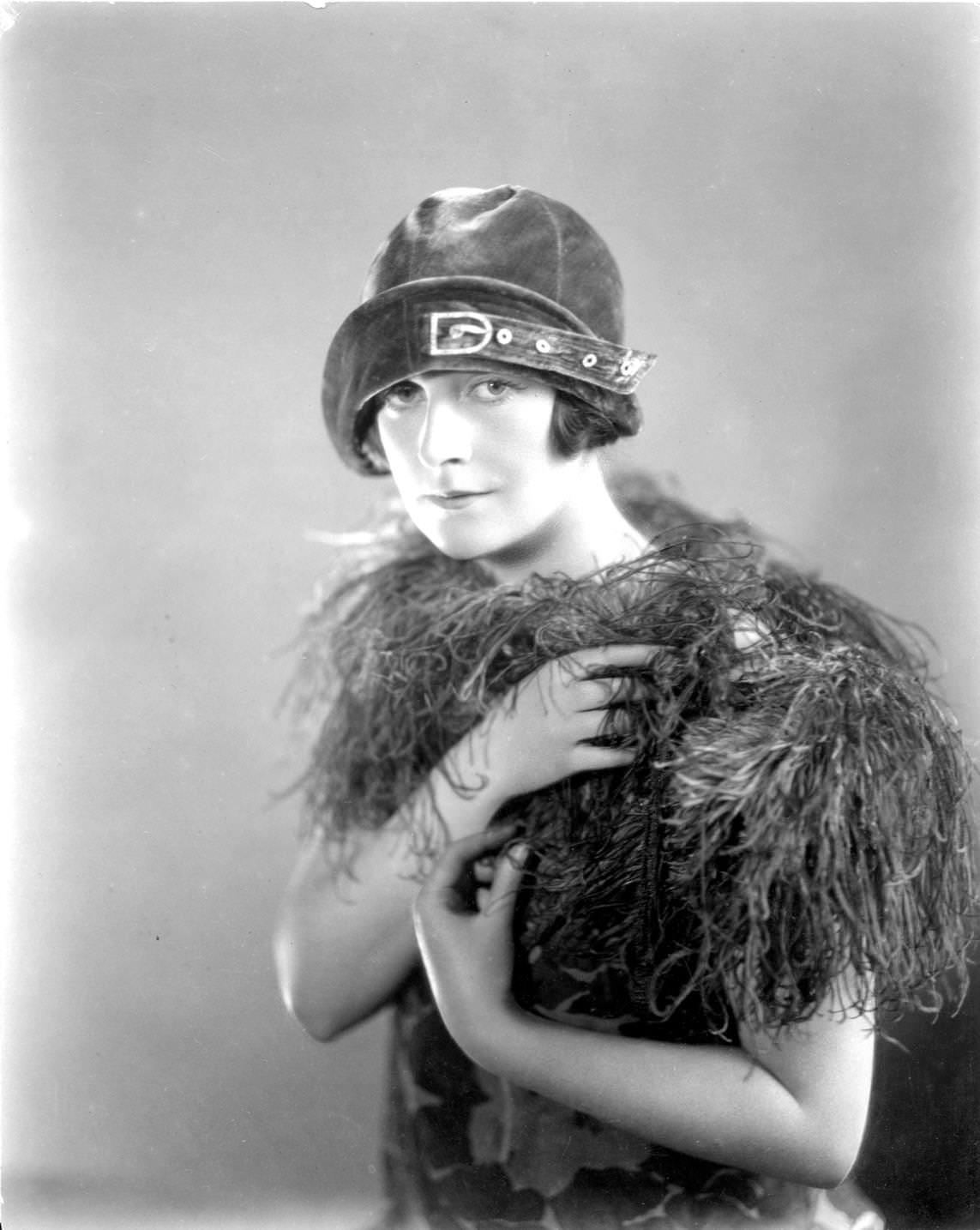 #121 British actress, Agnes Glynn wearing an ornamental cloche hat and a boa, 1925