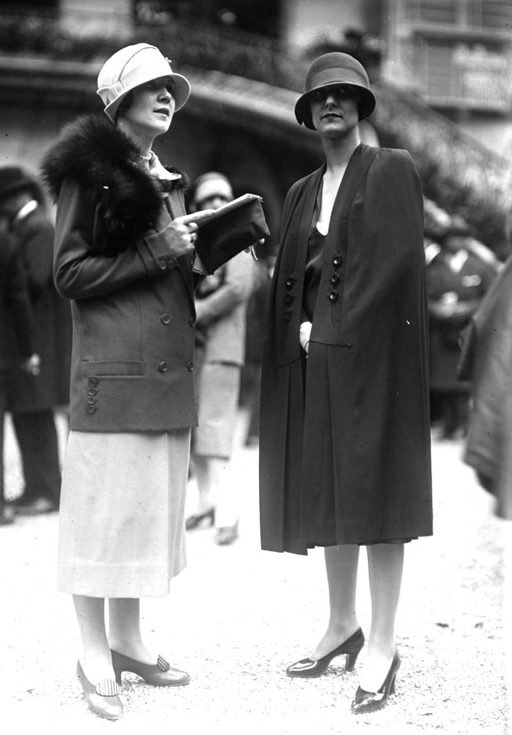 #148 A cape worn with a cloche hat and court shoes and a tailored suit of plain material suit with contrasting skirt, a fox fur and a cloche hat with a brim, 1924
