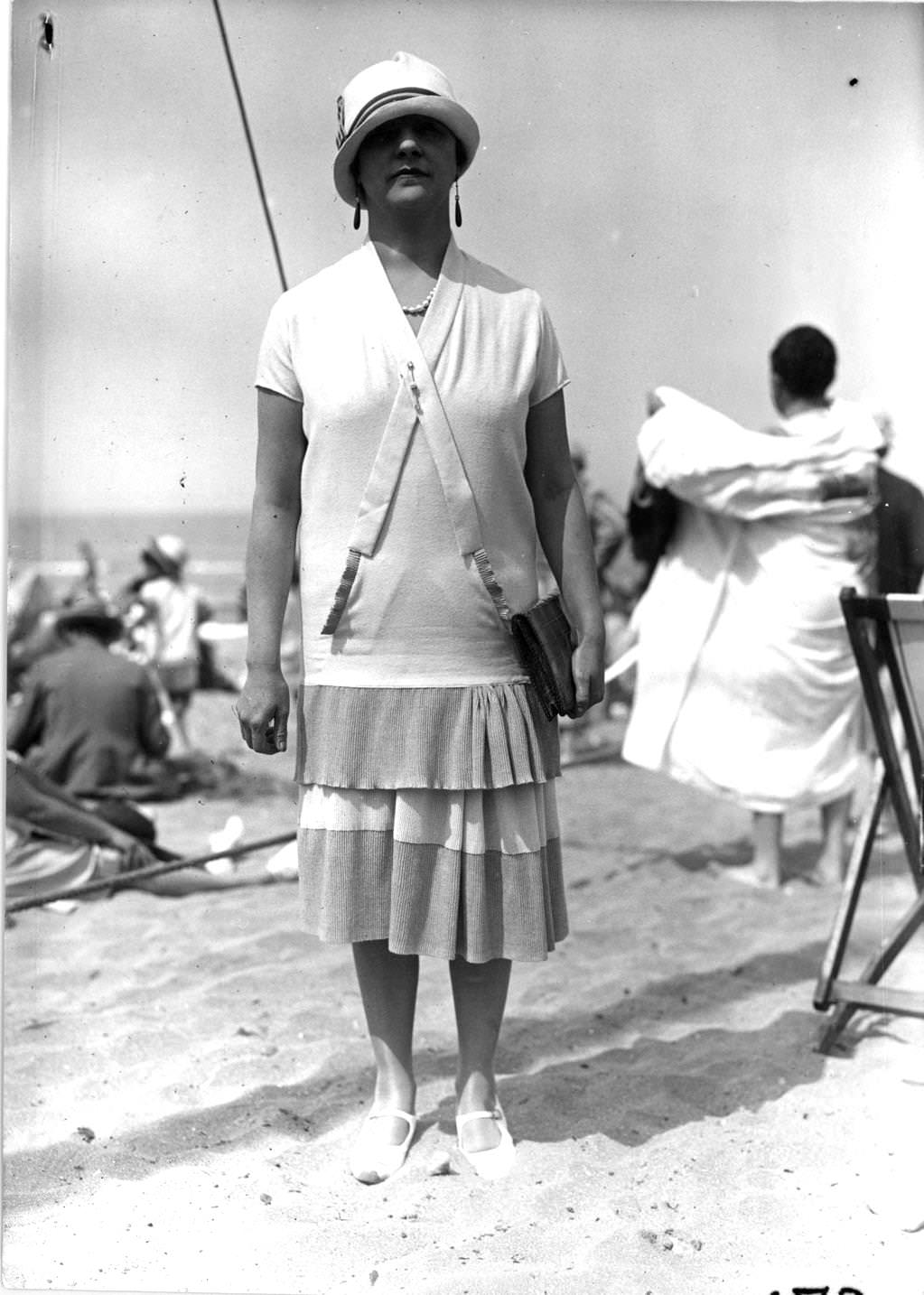 #152 Single-flounce tunic dress with gathers over the hip worn with a small-brimmed cloche hat and drop earrings, 1926