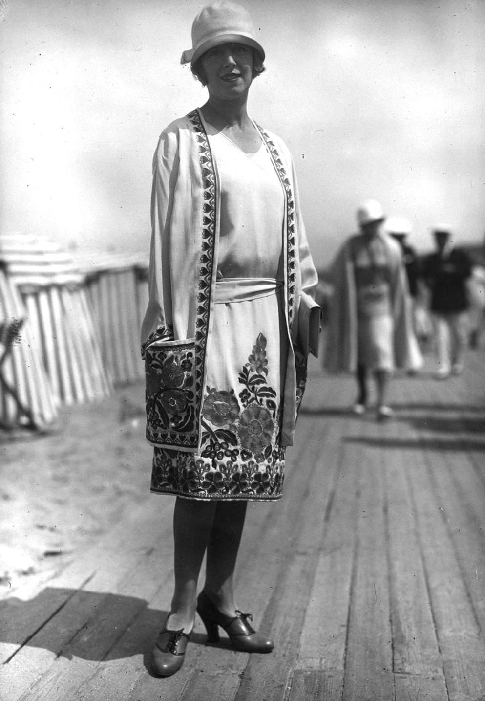#153 ummer outfit designed by Nicole Groult. A matching dress and three-quarter coat have flower embroidery round hems and on pocket. Outfit is completed with a cloche hat and lace-up court shoes, 1926