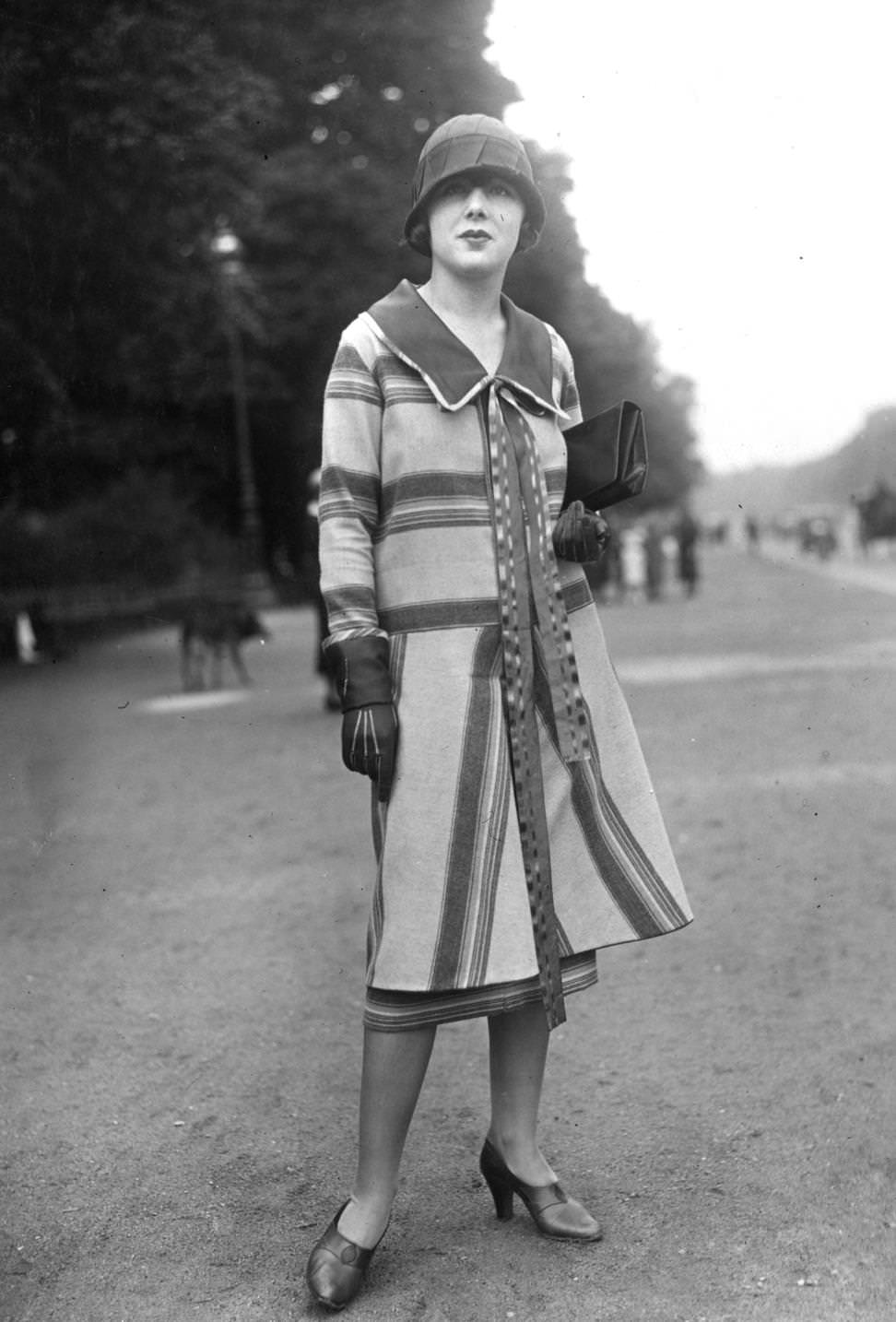 #175 Striped coat with wide collar. Cloche hat, clutch bag, gauntlets and high vamp court shoes complete an outfit designed by Jane Laffitte, 1925