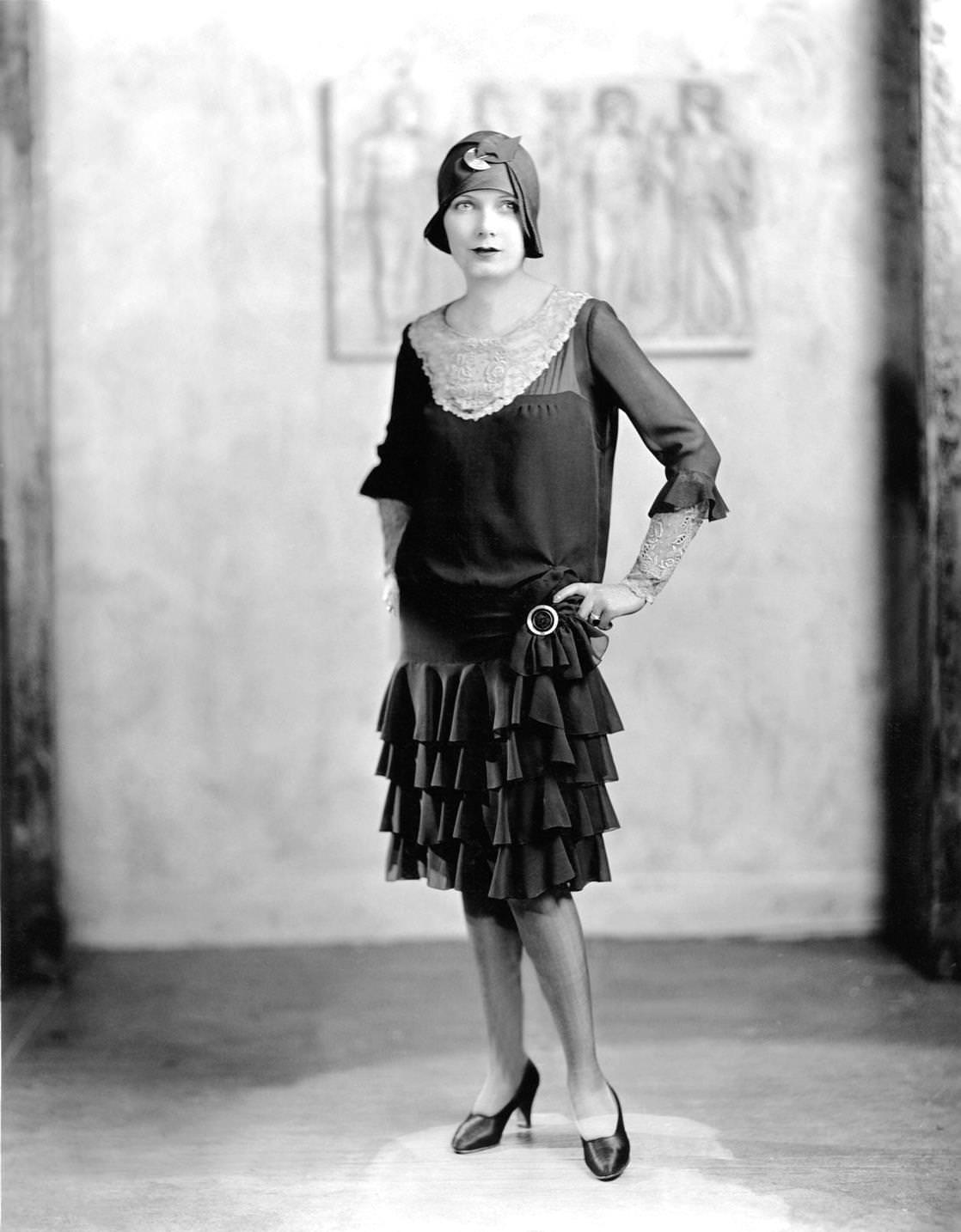 #8 Young woman in a ‘flapper’ dress and cloche hat posing for portrait with hands on hips, 1922