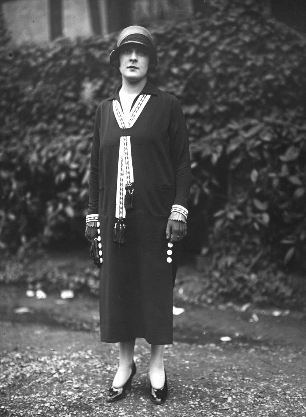 #49 A model wearing a dress with a lace stream resembling a tie across its breast and cloche hat, 1924