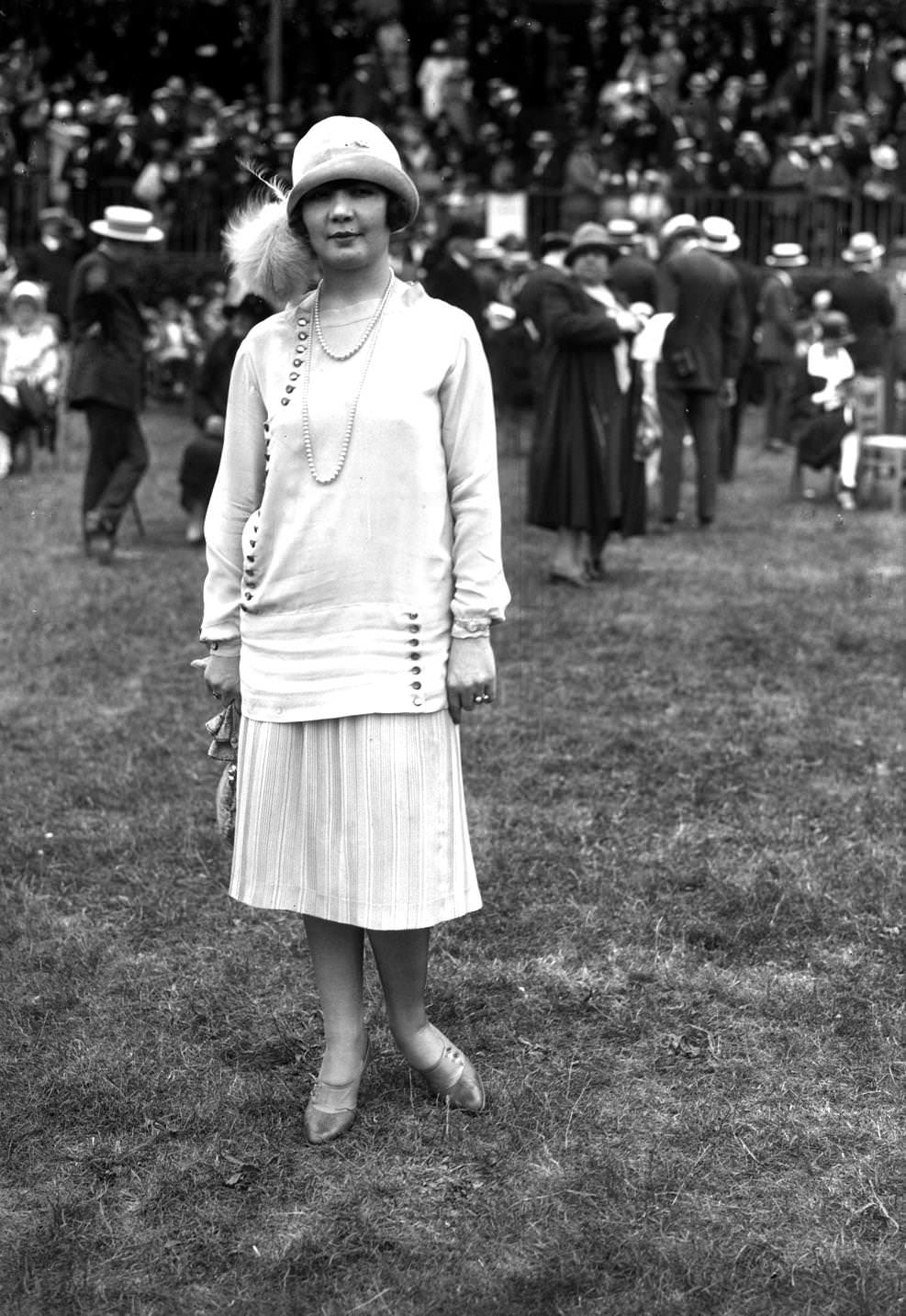 #56 Fashion at the races, in Auteuil. Striped skirt ensemble, long top trimmed with buttons. Paris, 1925