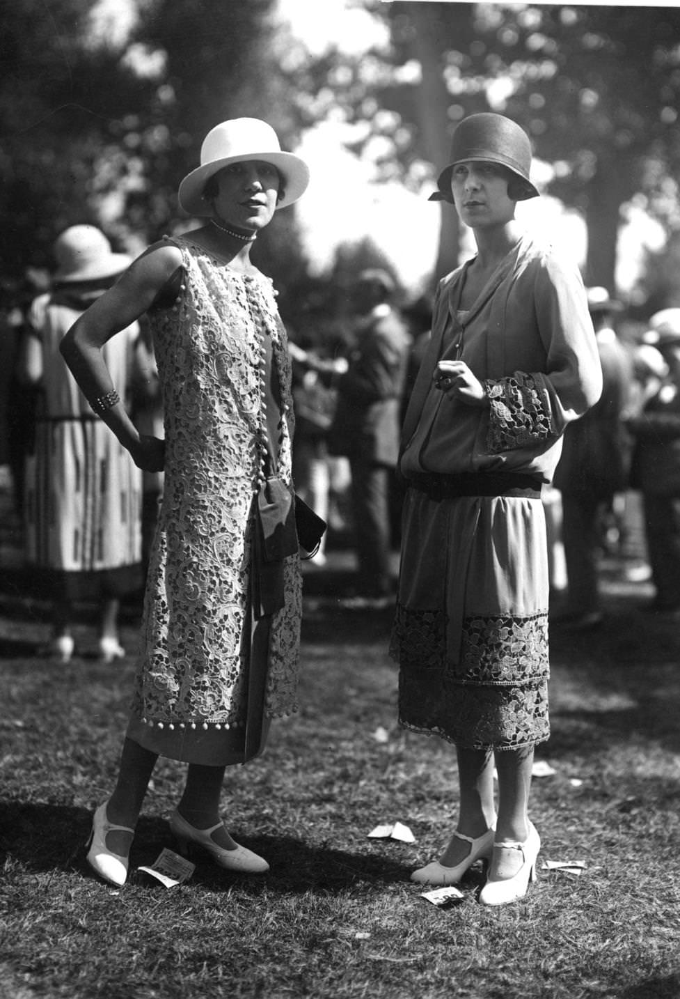 #59 A long sleeveless overdress of lace and a drop-waisted long sleeved tunic dress with lace inserts worn with a cloche hat, 1924