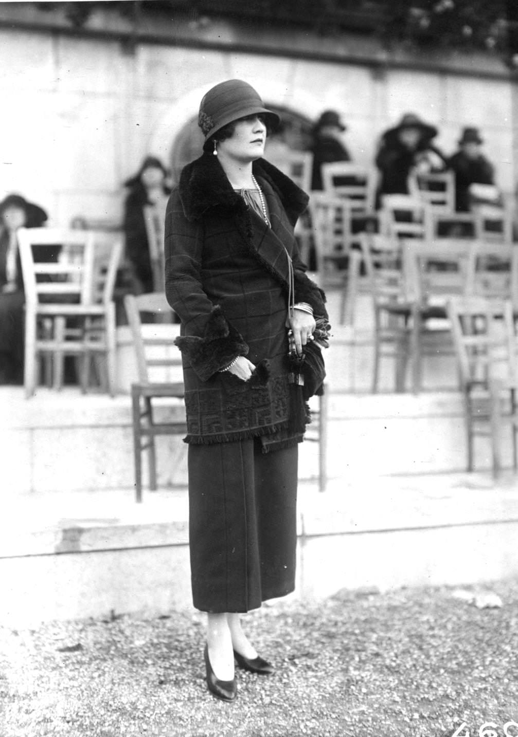 #81 A tailored three quarter length jacket trimmed with fur on lapels and cuffs is worn over an ankle-length skirt. A cloche hat completes the ensemble, 1923