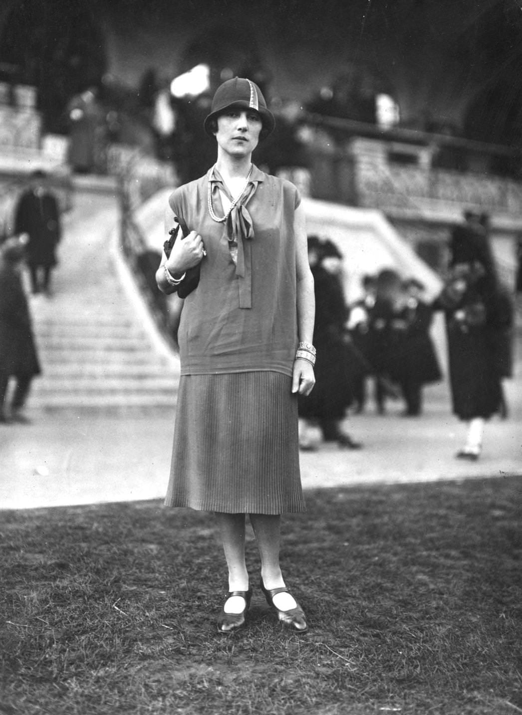 #91 Jeanne Lanlin models a hip-length silk tunic with tie neck, covering a knitted, ribbed skirt, and cloche hat, 1925