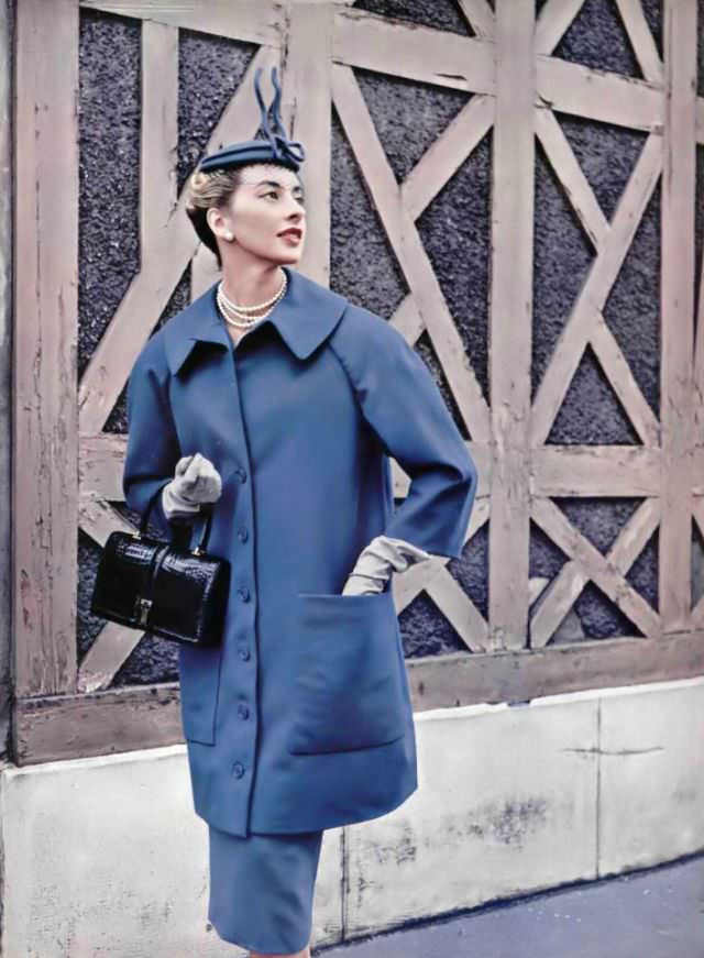 #36 Marie-Thérèse in 7/8 coat cut full in the back worn over slim jersey dress in same color by Jacques Fath, croc handbag by Amaryllis, 1954