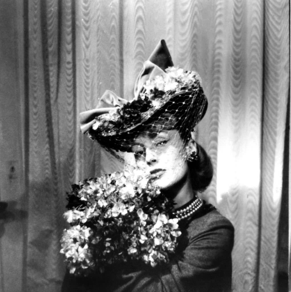 #52 Woman wearing a hat with a veil, holding a bouquet of flowers, Paris, 1943.