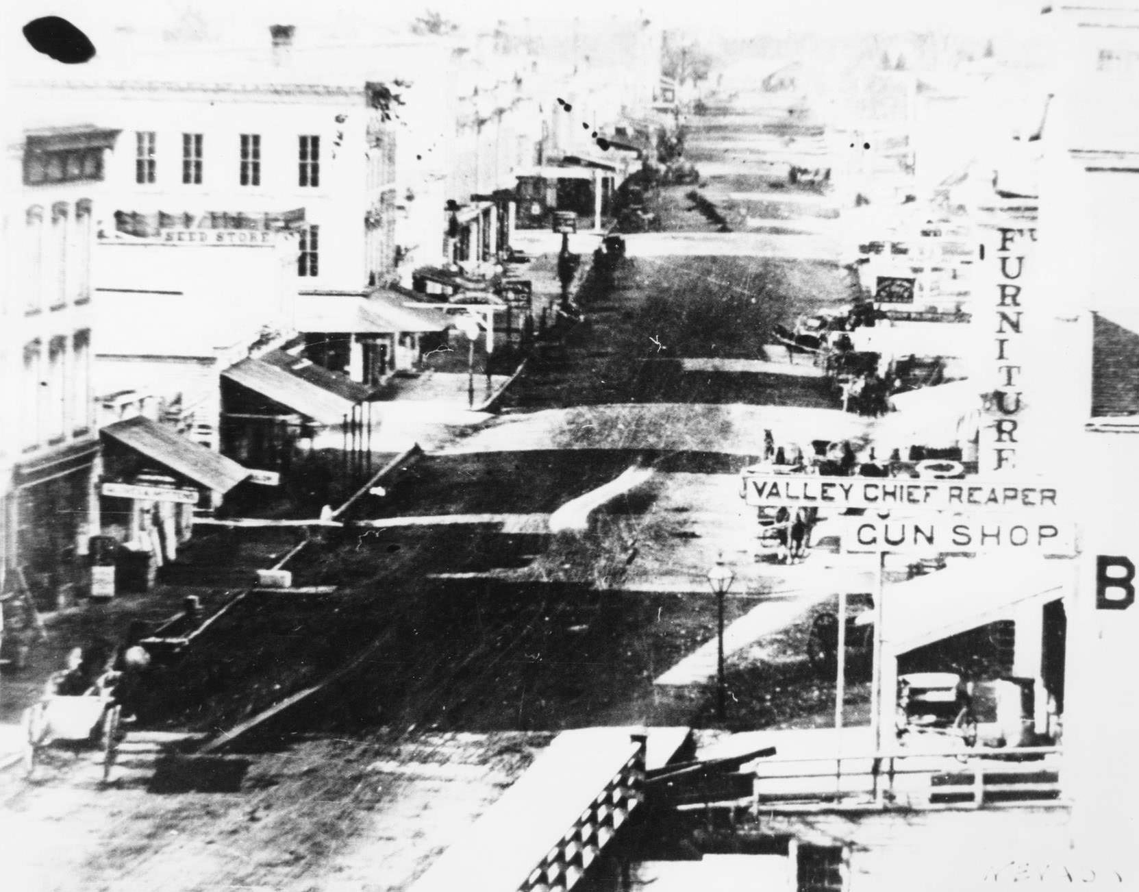 #53 Milwaukee Street looking west from the Jackman Building includes a horse and buggy, the Valley Chief Reaper Gun Shop, and a furniture store, 1850