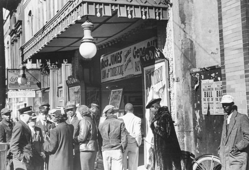 #51 A group of men and women standing outside a cinema waiting to be allowed in, with signs advertising “Buck Jones, Law of Tombstone, ” and “Gene Autry”; located on Beale Street in Memphis, 1939