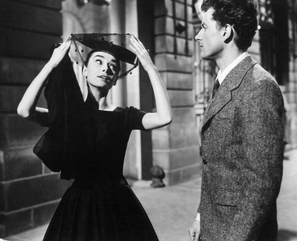 #35 Audrey Hepburn pulling her veil away as she speaks to a man in a scene from the film ‘Love In The Afternoon’, 1957.