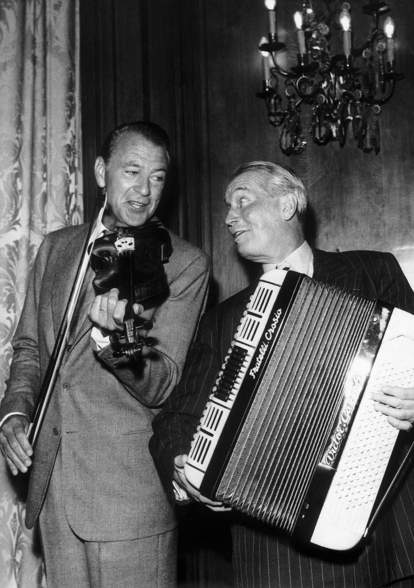 Maurice Chevalier and Gary Cooper, the two actors are playing music during the party held for the release of the movie ‘Love in the Afternoon’ on June 18, 1957 in Paris, France.