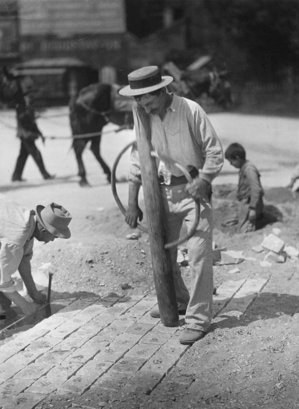 #65 A man pounds paving stones on a street into an even surface, Paris, 1900