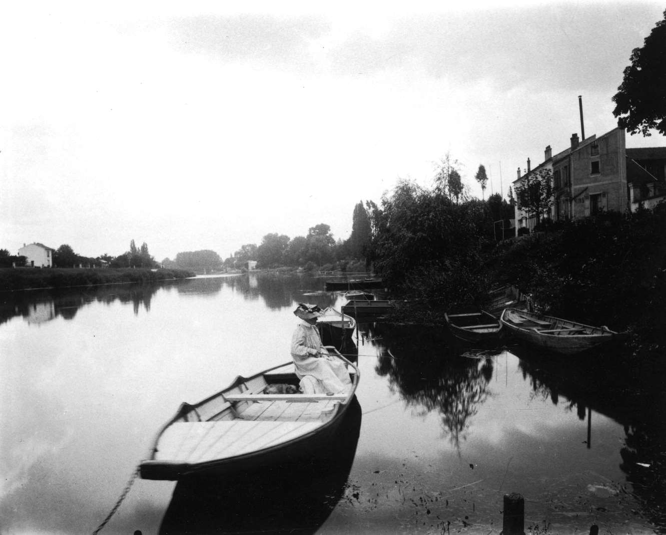 #87 Les Bords du Marne. A woman fishing on a rowboat in the Marne River, 1912