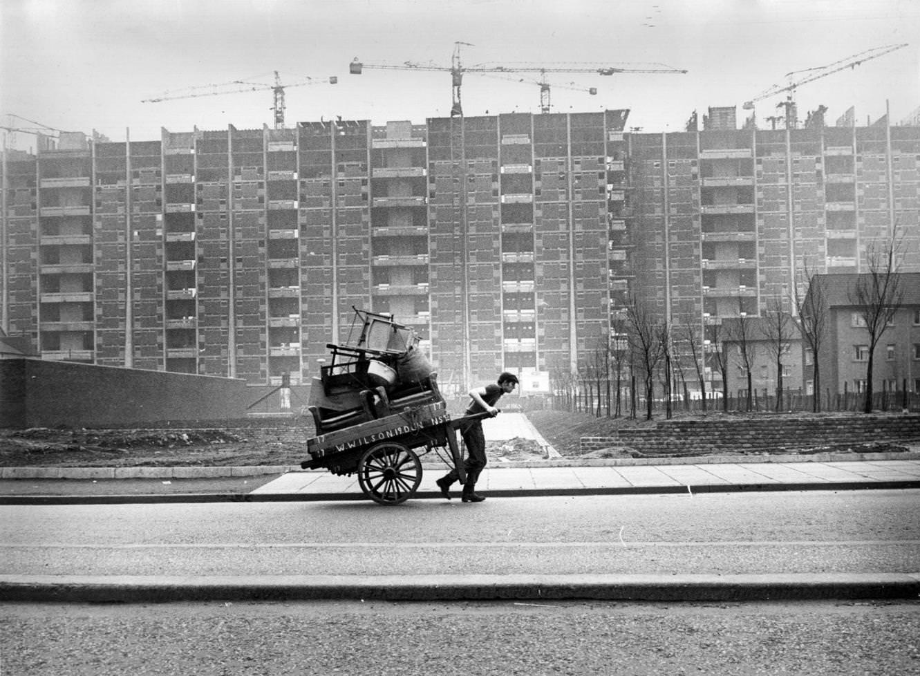 #123 A man pulling a hand cart past tower blocks under construction in the Gorbals area of Glasgow, 1960